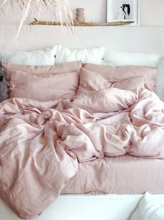 an unmade bed with pink sheets and pillows