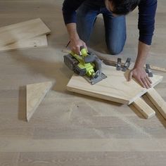 a woman kneeling down on the floor cutting wood