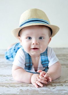 a baby laying on the floor wearing a hat