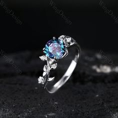 an engagement ring with blue topazte and white diamonds on the side, sitting on a black surface