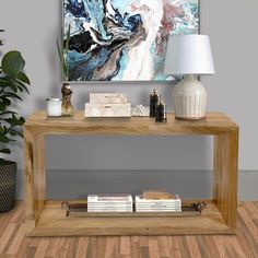 a wooden table with books on it in front of a large painting and potted plant