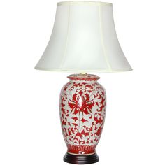 a red and white table lamp with a white shade on the top, sitting against a white background