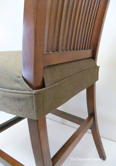 a close up of a wooden chair with a cushion on the seat and back rest