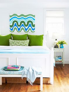 a white bed with green and blue pillows