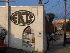 a building with an ad on it's side next to a red car parked in front of it