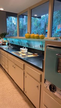 a large kitchen with lots of counter space and windows overlooking the trees in the background