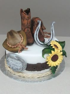 a cake decorated with cowboy hats and boots on top of a table next to a sunflower