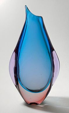 a blue and pink glass vase sitting on top of a white tableclothed floor