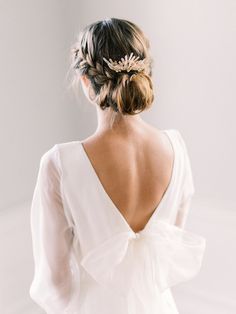 a woman wearing a white dress with a flower in her hair, looking back at the camera