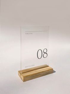 a clear acrylic sign with the number 08 on it's base and wooden stand