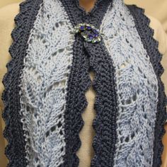 a woman wearing a blue and white knitted scarf on top of a mannequin