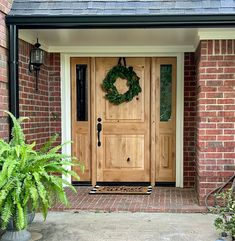 a wooden door with a wreath hanging on it's side and potted plants next to it