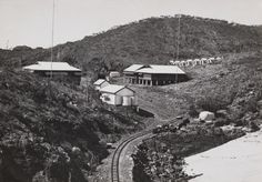 an old black and white photo of houses on the side of a hill with train tracks