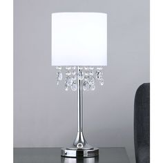 a chrome table lamp with a white shade on the base and crystal beads around it