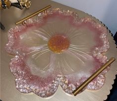 a pink glass dish sitting on top of a table next to some goldware and other items