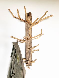 a coat rack made out of driftwood is hanging on the wall next to a jacket