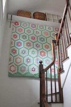 a stair case with a quilt on it and baskets above the bannister area