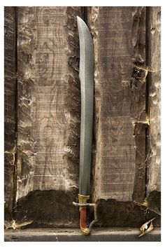 a large knife with a long blade sticking out of it's side on a wooden surface