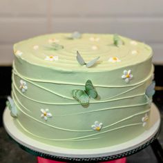 there is a green cake with butterflies on it