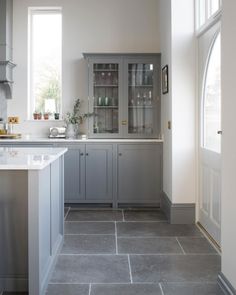 a kitchen with gray cabinets and white counter tops