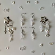 several pairs of earrings are displayed on a white surface with pearls and star shaped beads