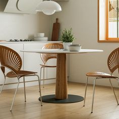 two chairs and a table in a room with white walls, wood flooring and windows