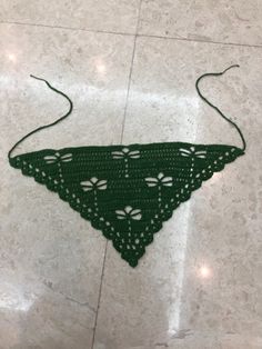 a green crocheted triangle on the floor