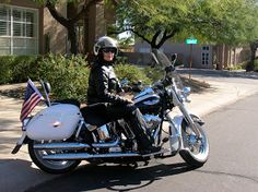 a woman riding on the back of a white motorcycle down a street next to trees