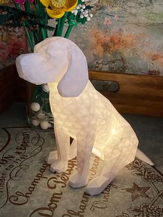 a white dog lamp sitting on top of a table next to a vase filled with flowers