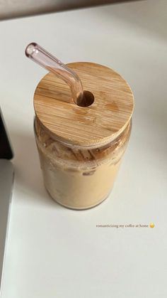 a glass jar filled with liquid sitting on top of a white table next to a laptop