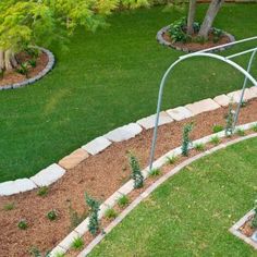 an aerial view of a garden with green grass and plants in the center, surrounded by stone edgings