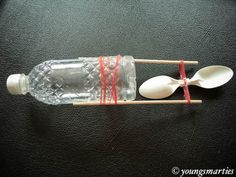 two plastic spoons with red string wrapped around them and a bottle filled with water