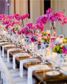 a long table with many vases filled with pink and purple flowers on top of it