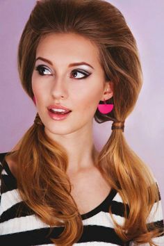 a woman with long blonde hair wearing pink earrings and black and white striped shirt, looking at the camera