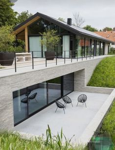 an outdoor patio with chairs and tables in front of a modern house on the hillside