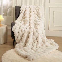 a large white blanket sitting on top of a chair next to a lamp in a room