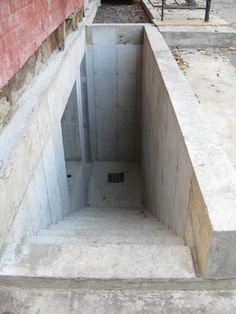 an open concrete pit sitting on the side of a building