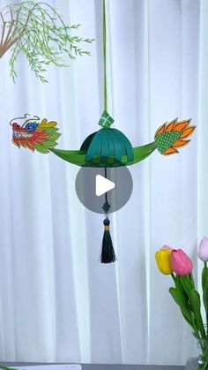 a vase filled with flowers next to a green lantern hanging from a ceiling fan over a window