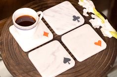 marble coasters with playing cards and a cup of coffee on a wooden tray next to flowers