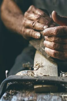 the hands of an elderly person are resting on a wooden bench