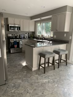 a kitchen with two stools in front of an island and stainless steel refrigerator freezer