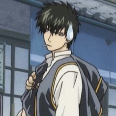 an anime character with black hair and white shirt standing in front of a blue building