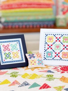 two framed pictures sitting on top of a quilt