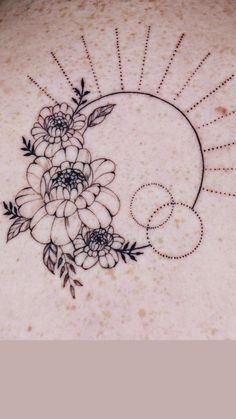 the back of a woman's neck with flowers and sunbursts on it