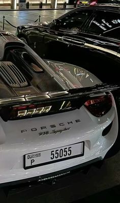 the back end of a white porsche sports car in a showroom with other cars