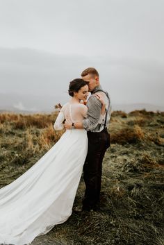 a bride and groom standing in the middle of a field