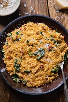 pasta with spinach and parmesan cheese in a skillet on a wooden table