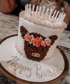 a birthday cake with candles on it and a teddy bear head in the top tier