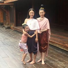 two girls and one girl are standing in front of an old wooden building with wood floors