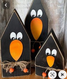 three bird houses with faces painted on them and string tied to the sides, sitting on top of a wooden table